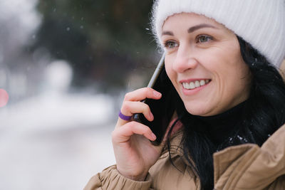 Cute girl talking on the phone outside in winter and smiling