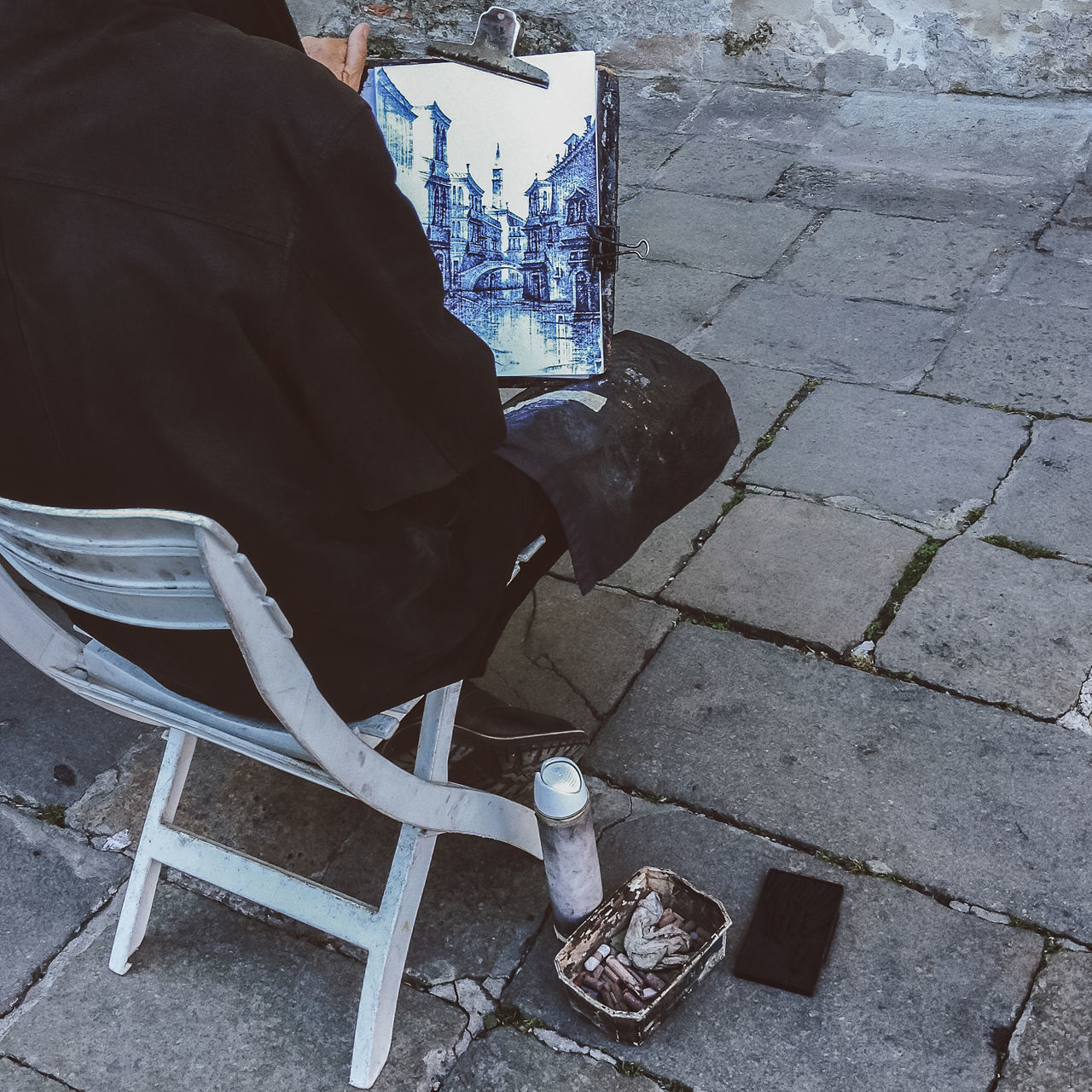 LOW SECTION OF MAN SITTING ON FOOTPATH IN STREET