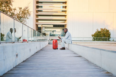 Traveler with a red suitcase and a cell phone