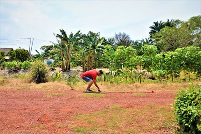 Side view of man bending on field against sky