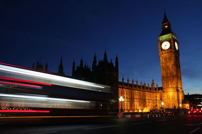 Blurred motion of bus leading towards illuminated big ben night