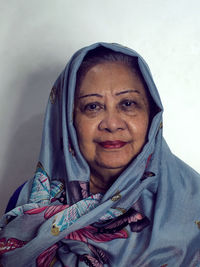 Portrait of smiling senior woman standing against wall