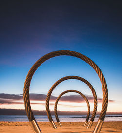 Metallic structure on beach against blue sky