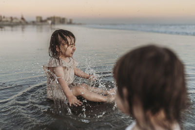 Happy 2 year old girl splashing in water at beach