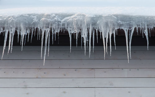 Building covered with icicles, closeup. ice stalactite hanging from roof, copy space. 