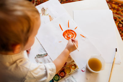 High angle view of boy drawing on paper at home