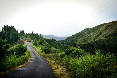 Road by mountains against cloudy sky