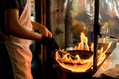 Midsection of chef preparing food in commercial kitchen