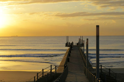 Pier over sea against sky during sunset