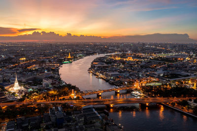 Aerial view of illuminated city against sky during sunset