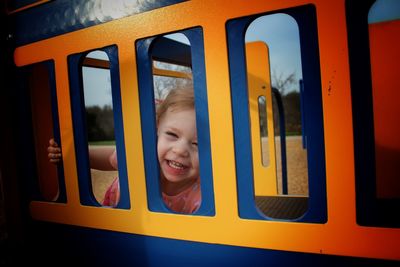 Portrait of happy girl looking through play equipment