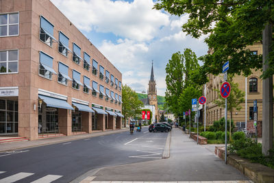 Road amidst buildings in city against sky