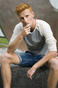 Portrait of young man looking away while sitting outdoors