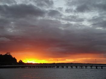 Silhouette of bridge over river during sunset