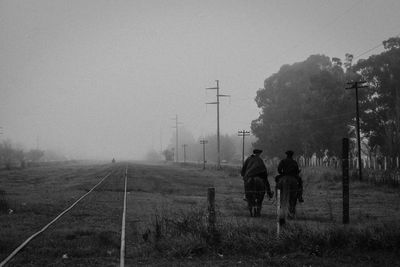 People standing on field in foggy weather