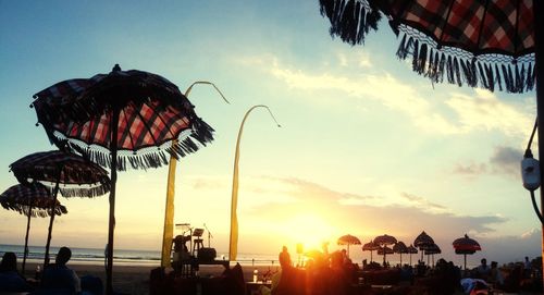 Ferris wheel at beach against sky during sunset