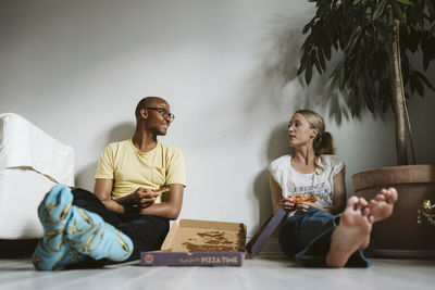 Couple sitting on floor and having pizza