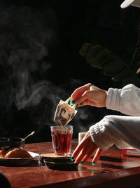 Cropped hands of woman preparing green tea