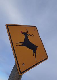 Low angle view of road sign against sky. deer sign