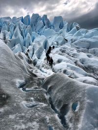 Rear view of hikers climbing on glaciers during winter