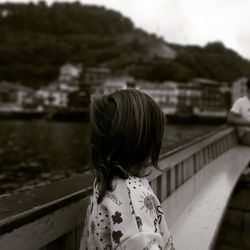 Girl looking away while standing by railing