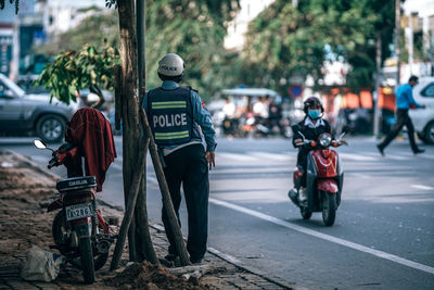 Rear view of people riding motorcycle on road