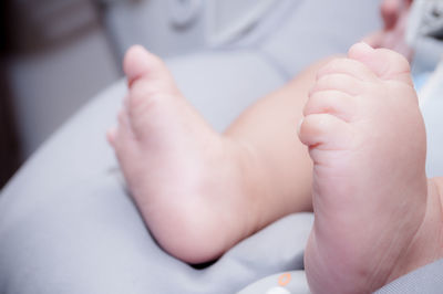 Low section of baby lying on bed