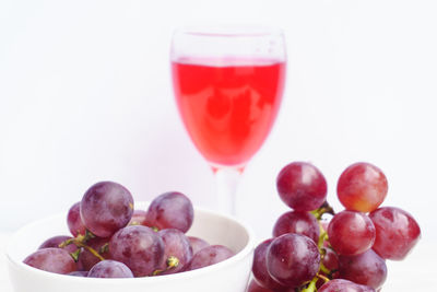 Close-up of red grapes with juice in glass on table