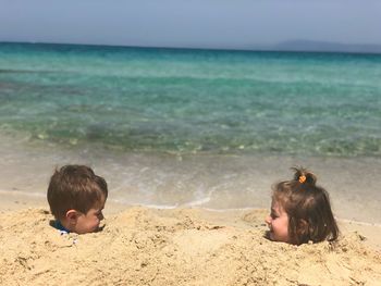 Siblings buried in sand at beach