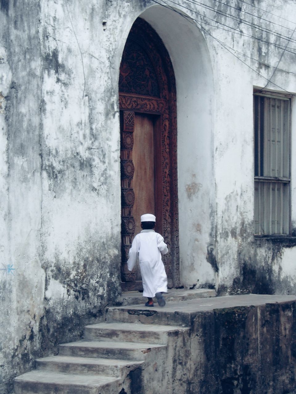 architecture, white, built structure, one person, blue, building exterior, wall, building, winter, entrance, rear view, door, adult, day, full length, staircase, temple, sitting, wall - building feature, clothing, arch, lifestyles, ancient history, window, religion, outdoors, men, old, women, belief, spirituality