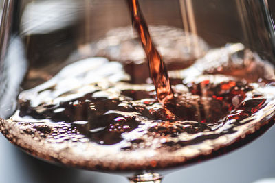Pouring red wine into a wine glass with bubbles, close up