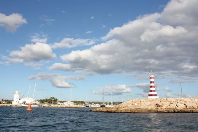 Lighthouse by sea against sky