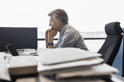 Side view of businessman using laptop at desk in office