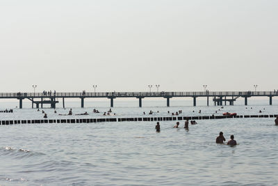 People swimming in sea against clear sky