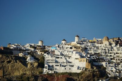 Buildings in city against clear blue sky