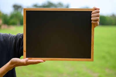 Midsection of person holding blank writing slate