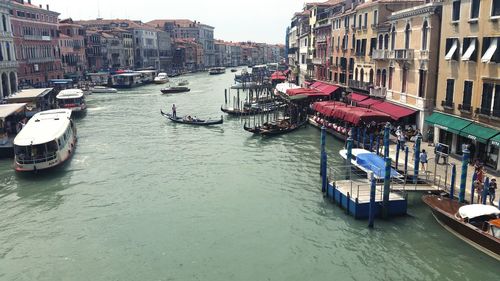 Boats moored in canal amidst buildings in city