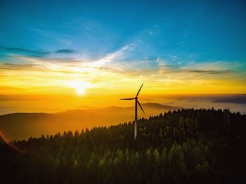Silhouette of windmill on field against sky at sunset