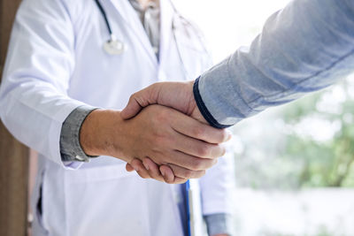 Midsection of man shaking hands with doctor