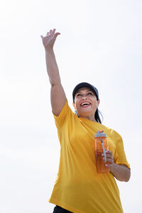 Smiling man holding yellow while standing against sky