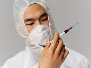 Doctor holding syringe against white background