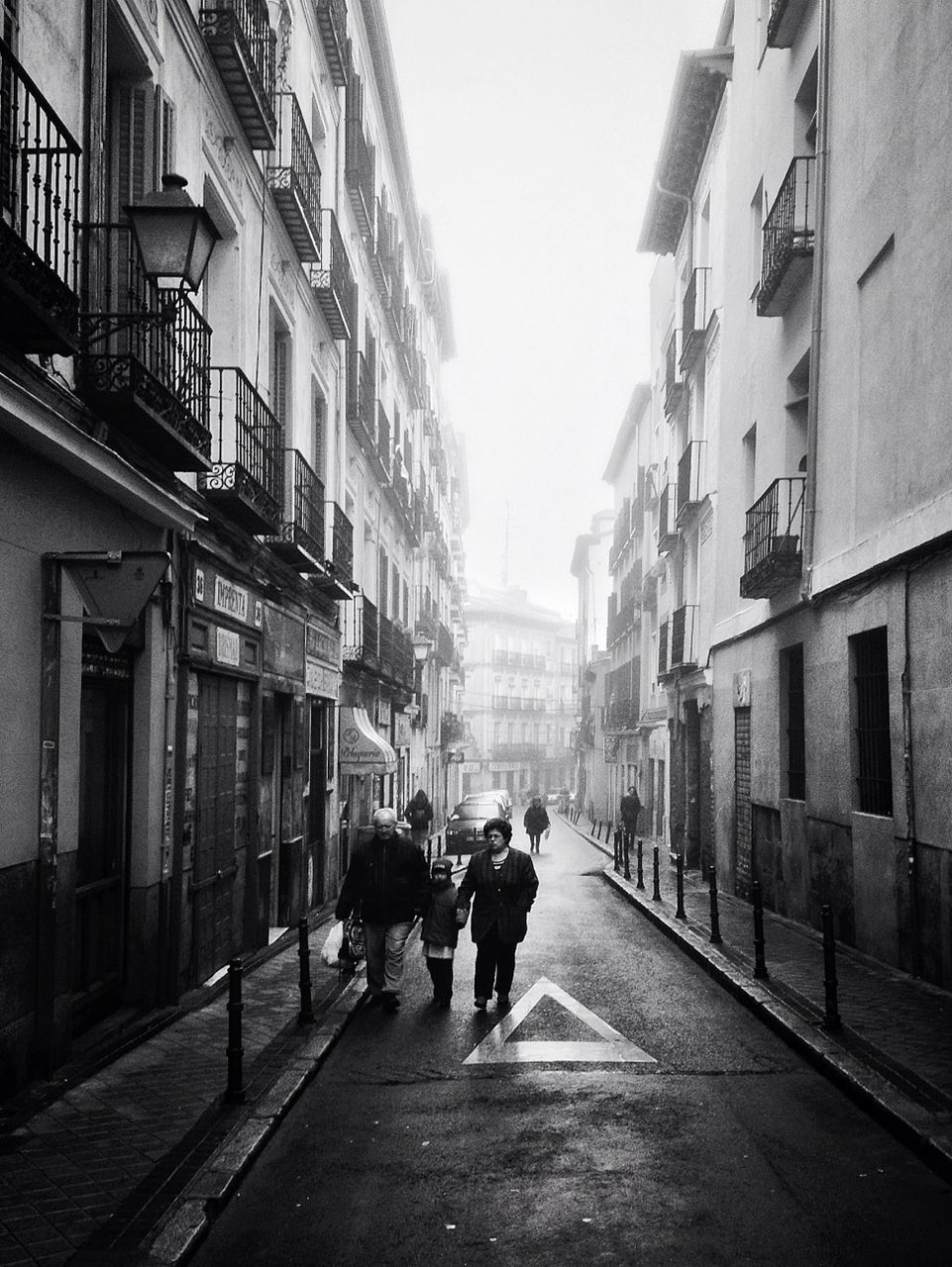 building exterior, architecture, built structure, street, city, the way forward, walking, men, residential structure, residential building, city life, building, diminishing perspective, person, clear sky, lifestyles, road, full length, day