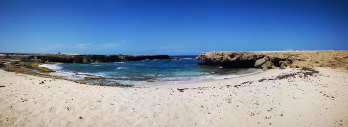 Scenic view of beach against clear blue sky