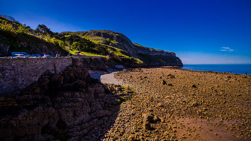 Rock formation on beach against clear blue sky