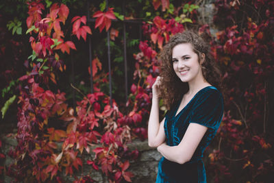 Beautiful curly hair girl in a dark blue velvet dress in an autumn park