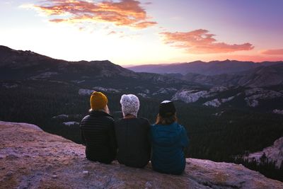 Rear view of people looking at mountains during sunset