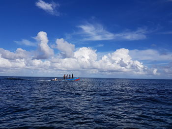 People sailing in sea against sky