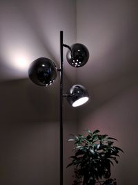 Low angle view of illuminated lighting equipment hanging on wall at home