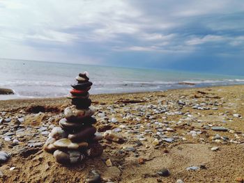 Stack of pebbles on beach against sky