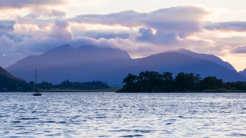 Scenic view of lake by mountains against sky